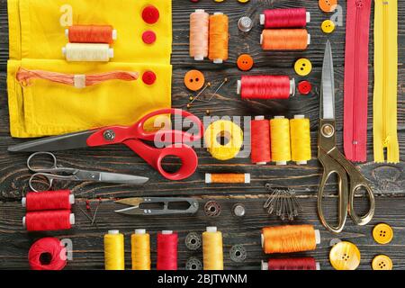 Composition with sewing threads, fabric and accessories on wooden background, top view Stock Photo