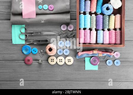 Composition with sewing threads, fabric and accessories on wooden background, top view Stock Photo
