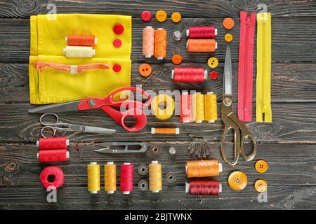 Composition with sewing threads, fabric and accessories on wooden background, top view Stock Photo