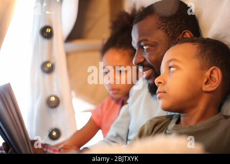 African American man reading bedtime story to his children at home Stock Photo