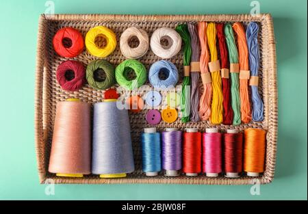 Wicker tray with different types of threads on color background Stock Photo