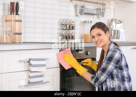 Young woman cleaning oven in kitchen Stock Photo