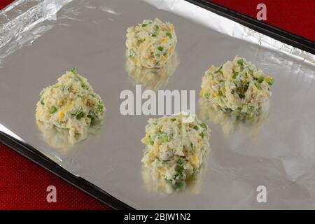 Four raw cheese biscuits with jalapenos on aluminum foil on balking sheet ready for baking Stock Photo