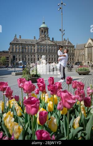 couple on a city trip to Amsterdam, men and woman relaxing by the canals of Amsterdam during Spring 2020 April in Europe Netherlands Stock Photo