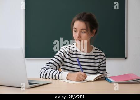 Cute teenager girl doing homework in classroom Stock Photo