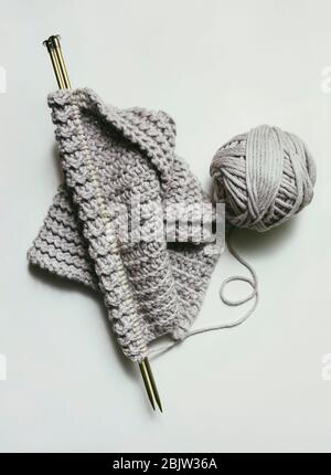 Partially knitted scarf with gray ball of yarn and knitting needles Stock Photo