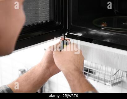 Young man repairing microwave oven, closeup Stock Photo