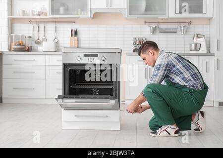 Young man repairing oven in kitchen Stock Photo