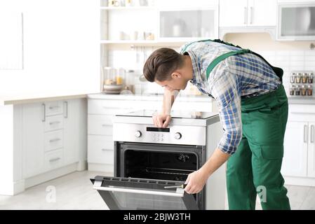 Young man repairing oven in kitchen Stock Photo