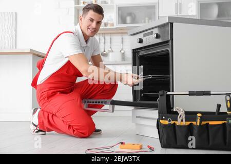Young man repairing oven in kitchen Stock Photo