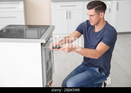 Young man repairing oven in kitchen Stock Photo