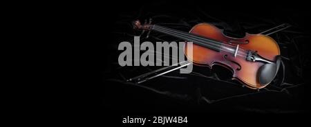 Shiny violin and bow isolated on black velvet  background with copy space Stock Photo