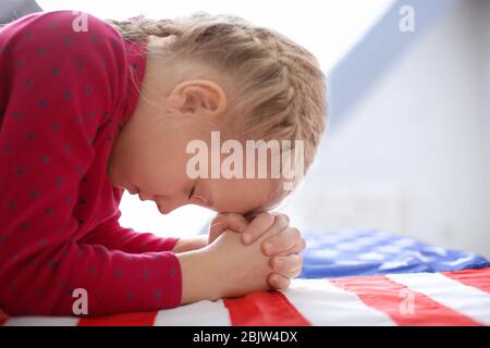 Cute little girl praying over American flag Stock Photo