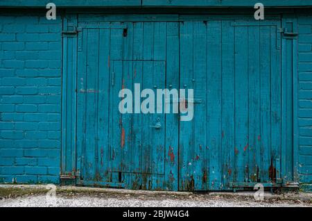 Old wooden gate and wall painted in green blue color. Weathered wood planks with rotten dirty bottom parts. Grunge distressed wooden background with c Stock Photo