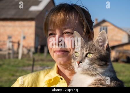 Woman plays with her cat in the backyard of the house in spring Stock Photo