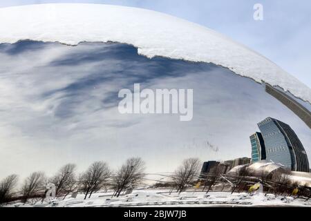 CHICAGO - January 7: The Cloud Gate also known as the Bean covered in snow with a partial view of the nearby cities skyline and Jay Pritzker Pavilion. Stock Photo