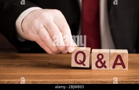 A Q & A or question and answer concept of the phrase spelled out in wooden blocks by a male business hand Stock Photo