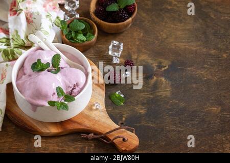 Homemade Organic Ice Cream with Mint. Blackberry ice cream in white bowl on a rustic table. Copy space. Stock Photo