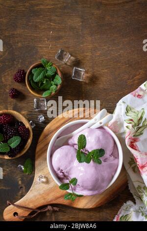 Homemade Organic Ice Cream with Mint. Blackberry ice cream in white bowl on a rustic table. Top view flat lay background. Copy space. Stock Photo