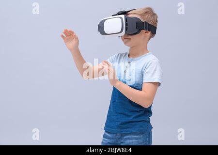 Cute boy with virtual reality headset on color background Stock Photo