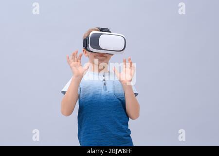 Cute boy with virtual reality headset on color background Stock Photo