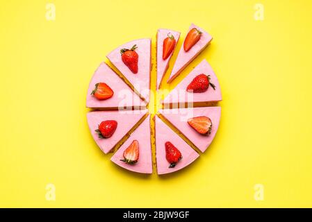Strawberry cheesecake sliced in unequal pieces, on a yellow seamless background. Flat lay with no-bake strawberry cake. Berry gelatine creamy dessert Stock Photo