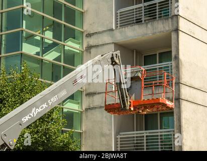 CARDIFF, WALES - JULY 2018: Hydraulic lift platform 'cherry picker' vehicle being used to clean the outside of an apartment building in Cardiff Bay. Stock Photo