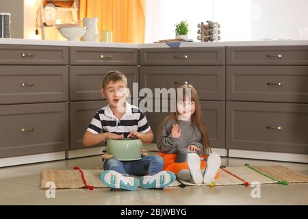 Cute little musicians playing drums on kitchenware at home Stock Photo