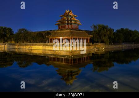 Northwestern tower of the Forbidden City Palace Museum in Beijing, China, reflecting in the water moat at night Stock Photo