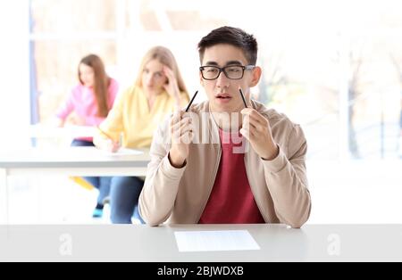 Nervous Asian student with broken pencil at exam in classroom Stock Photo