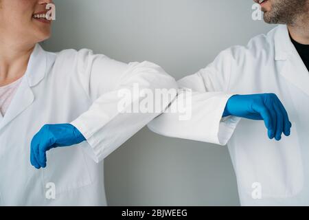 Elbow bumping. A new way of greeting to prevent the spread of the coronavirus (COVID-19). Two doctors bump elbows instead of greeting with a hug or a Stock Photo