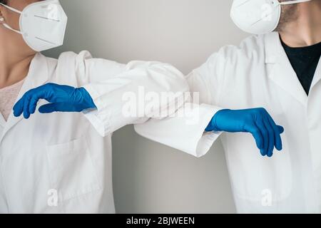 Elbow bumping. A new way of greeting to prevent the spread of the coronavirus (COVID-19). Two doctors bump elbows instead of greeting with a hug or a Stock Photo