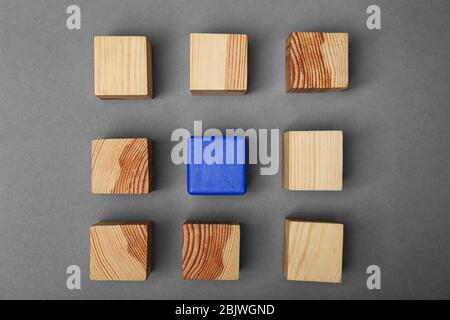 Wooden cubes and one different on grey background Stock Photo