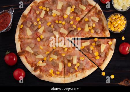 Pizza with chicken, pineapple and corn on dark background. Stock Photo