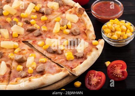 Pizza with chicken, pineapple and corn on dark background. Stock Photo