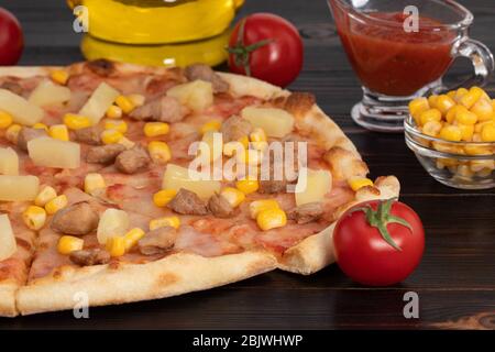 Pizza with chicken, pineapple and corn on dark background. Stock Photo
