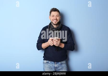 Young man in warm clothing on color background. Ready for winter vacation Stock Photo