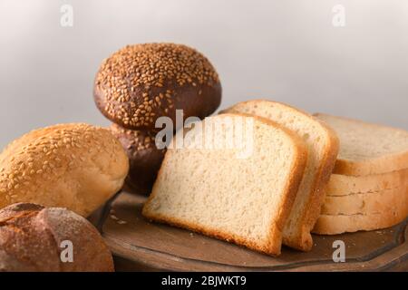Variety of fresh tasty bread on table against light background Stock Photo