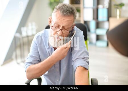 Senior man talking on mobile phone while working in office Stock Photo