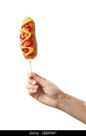 Woman holding tasty corn dog with ketchup and mustard on white background Stock Photo