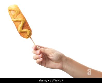 Woman holding tasty corn dog with mustard on white background Stock Photo