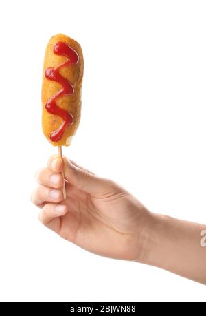 Woman holding tasty corn dog with ketchup on white background Stock Photo