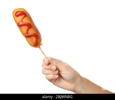 Woman holding tasty corn dog with ketchup on white background Stock Photo