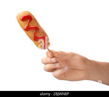 Woman holding tasty corn dog with ketchup on white background Stock Photo