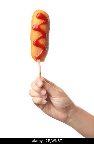 Woman holding tasty corn dog with ketchup on white background Stock Photo