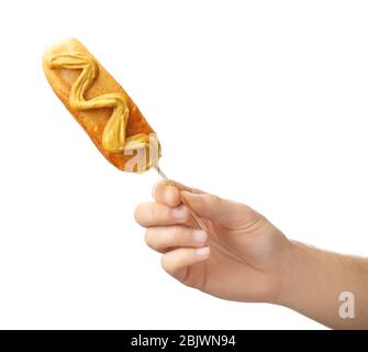 Woman holding tasty corn dog with mustard on white background Stock Photo