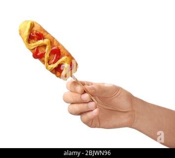 Woman holding tasty corn dog with ketchup and mustard on white background Stock Photo