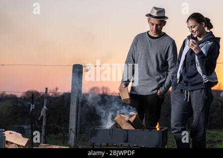 Couple of friends having barbecue, cooking food in the beautiful place Stock Photo