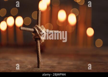 Wooden cross on table against defocused lights Stock Photo