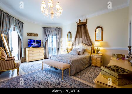 Large cozy bedroom in classic style, beige furniture, rugs and mirrors. Stock Photo